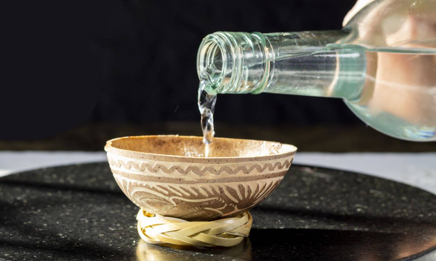 Raicilla being poured into a carved gourd - a traditional vessel made from the outside of a dried fruit.