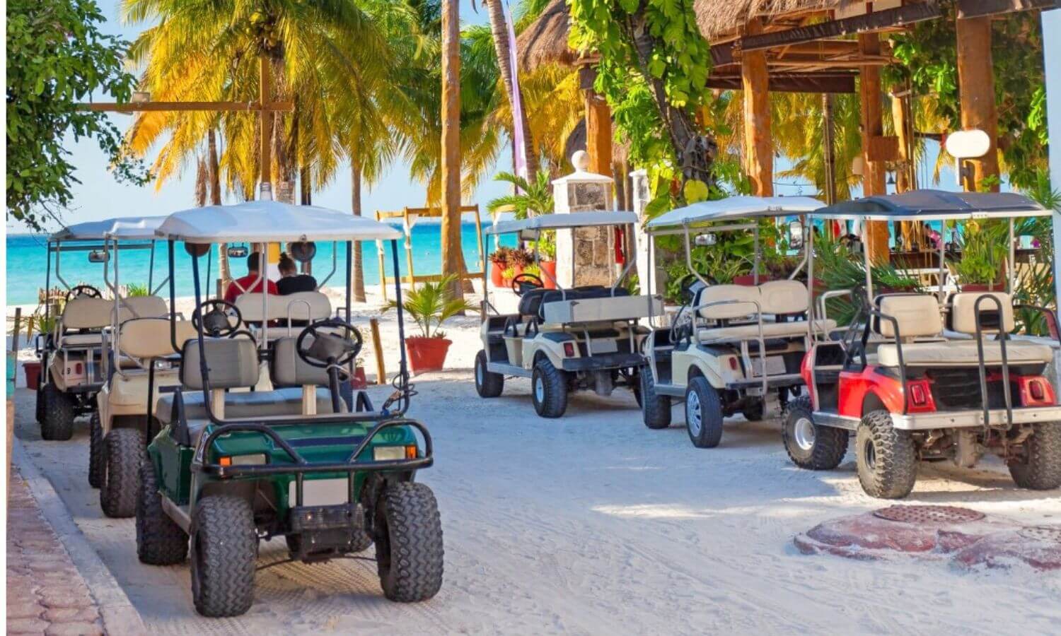 Golf carts parked on a sandy street by a beach club on Isla Mujeres.