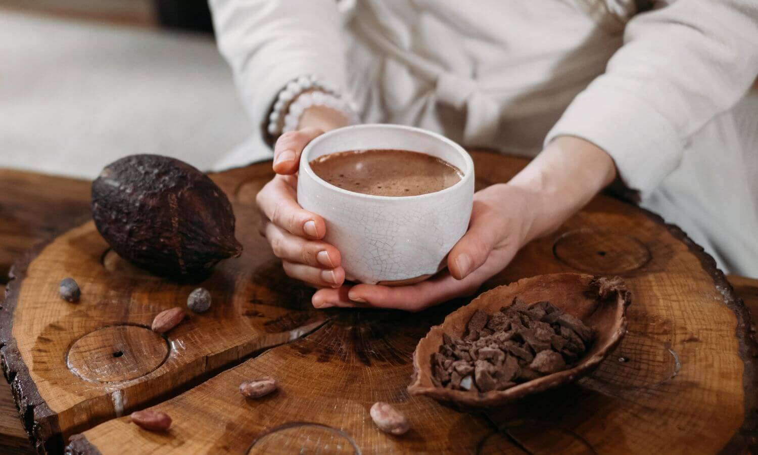 A lady holding a cup of hot chocolate with some cocoa pods and beans at the Festival de Chocolate in Villahermoso