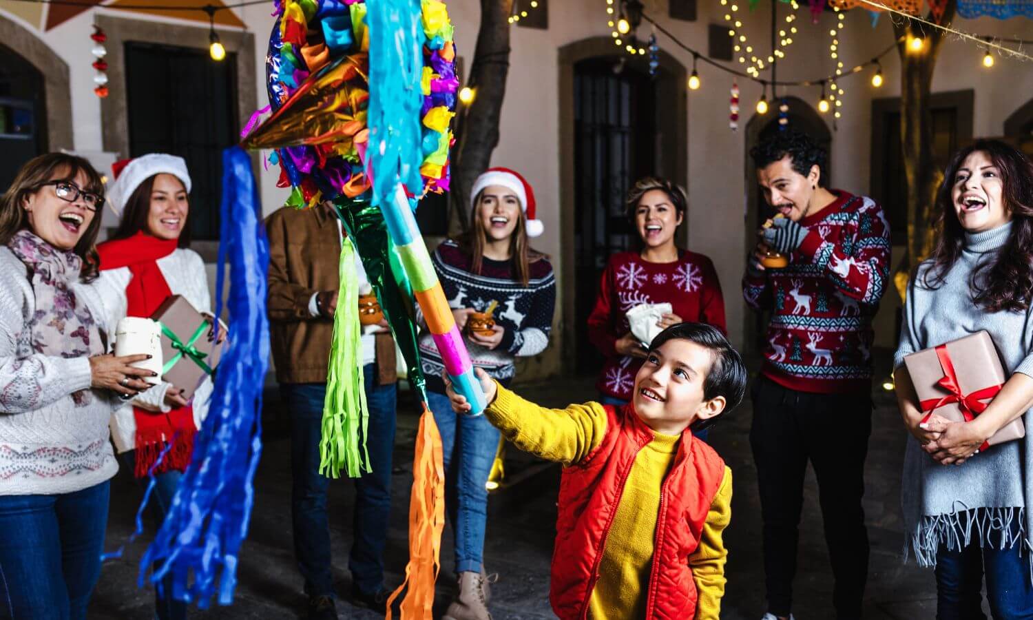A family watching a boy strike a Piñata, a Christmas Tradition in Mexico