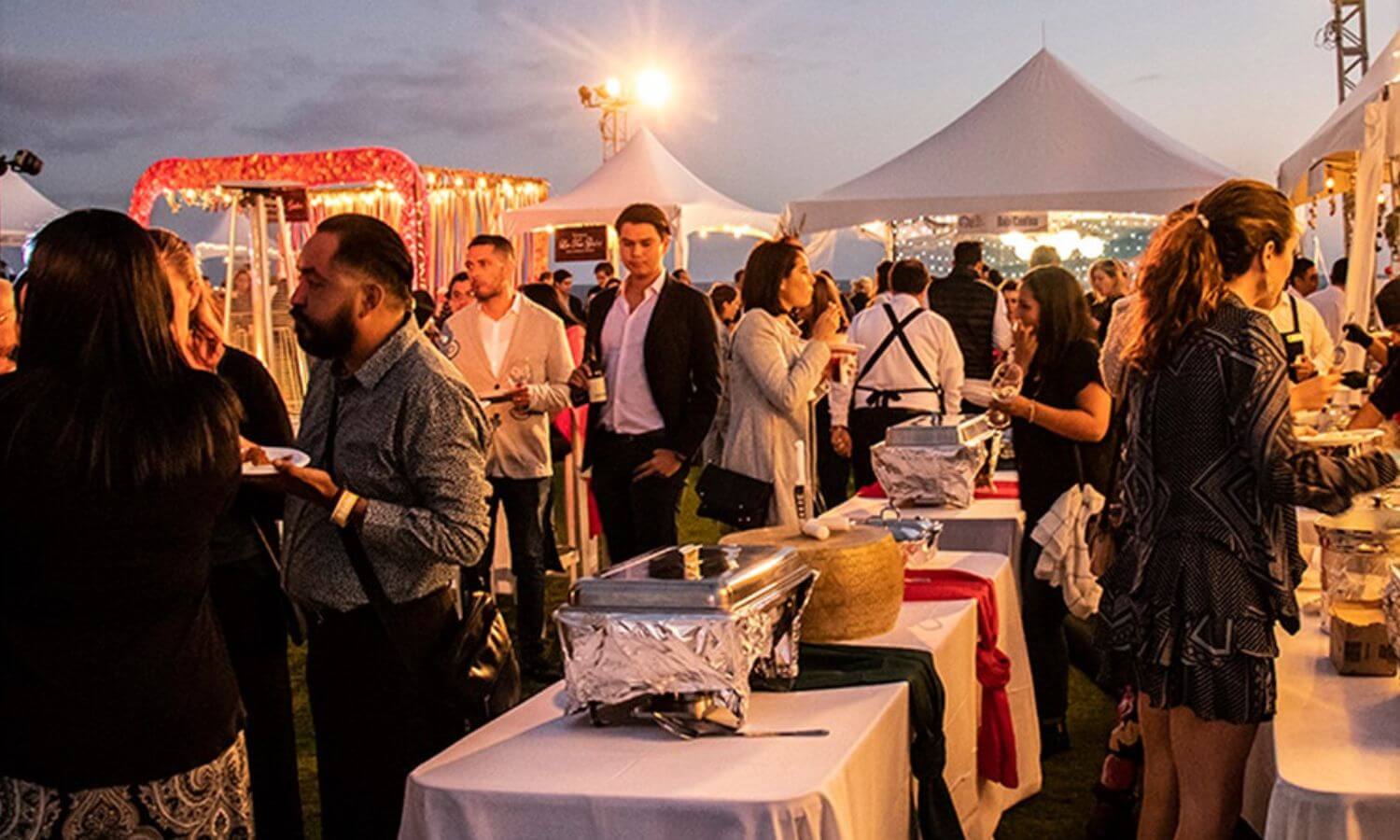 People mingling and sampling food in the evening at the Sabor a Cabo Culinary Festival