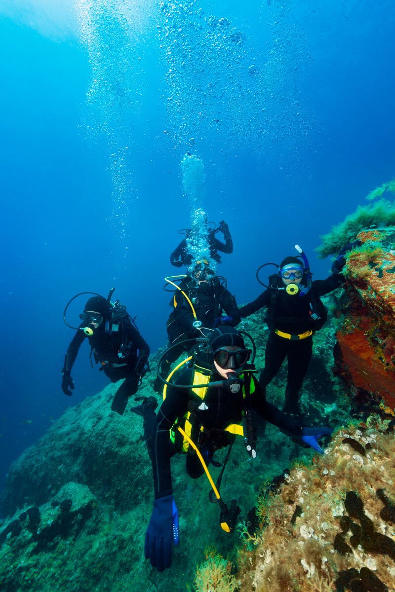 5 divers by the reef on a group dive off Cozumel island.