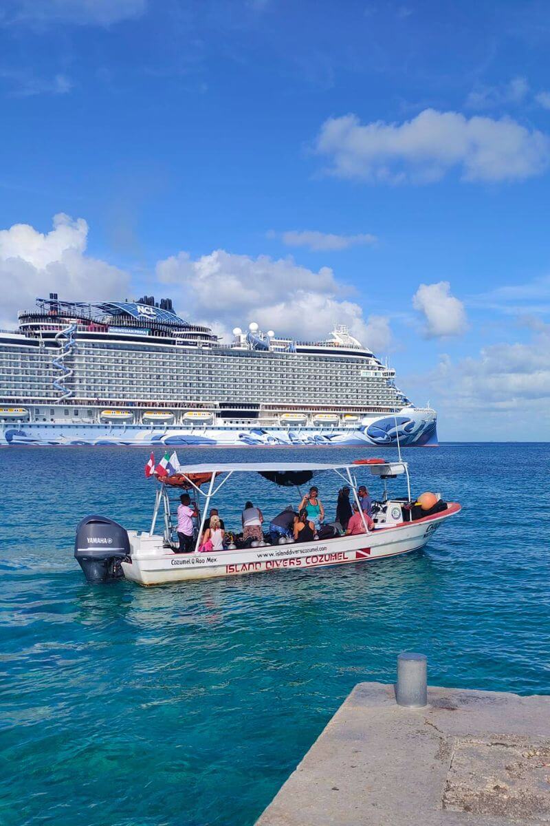 An Island Divers boat leaving for a dive with a cruise ship in the background.