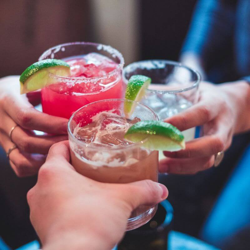 Three flavors of margaritas being held by women.