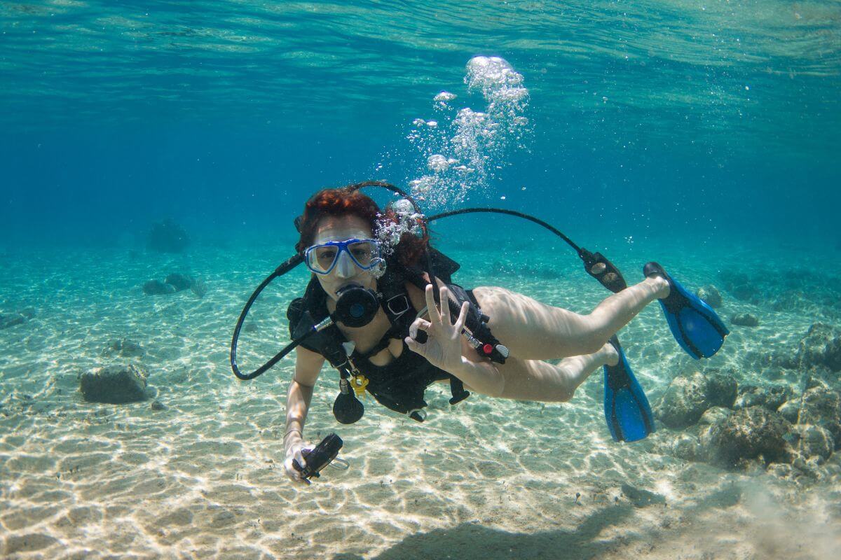 A lady scuba diving in the shallow ocean off the coast.