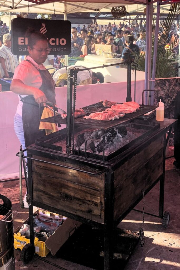 Meat being grilled on a larger wood fired grill at the Mexican Caribbean food festival.