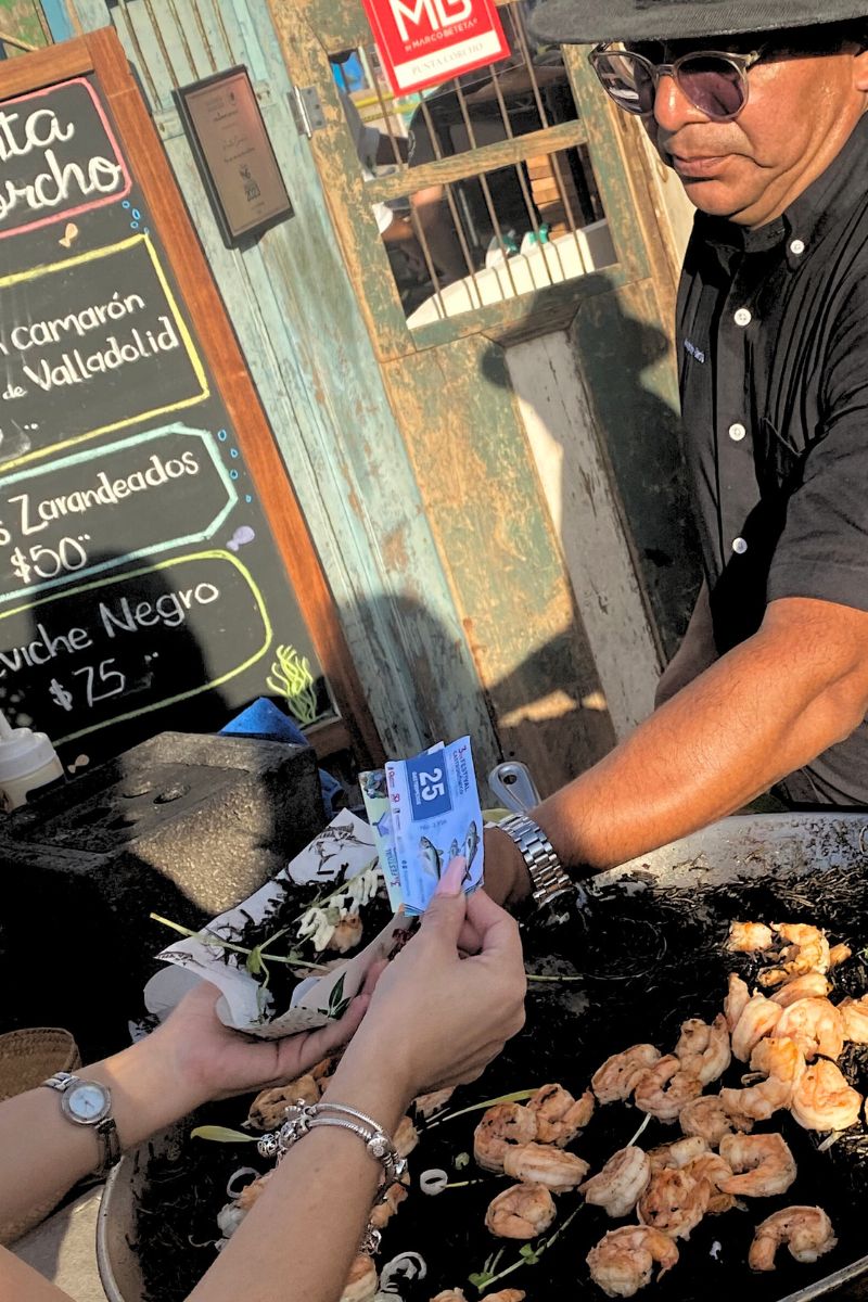 Paying for a plate of black paella with tickets at the Mexican Caribbean Food Festival