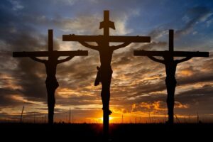 Three statues of men being crucified in front of a sunset. These are displayed during Easter in Mexico.
